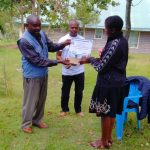 Secretary to the council of elders awarding some of the best Ogiek students who participated in a climate essay competition supported by global green grants